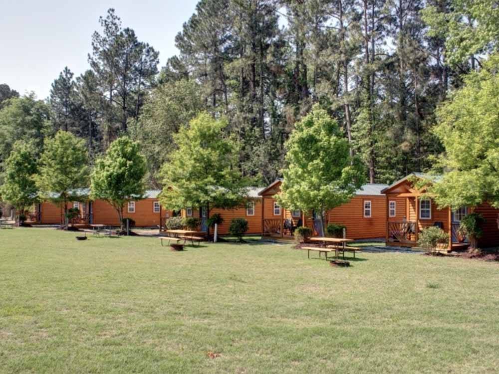A row of rental log cabins at FAYETTEVILLE RV RESORT & COTTAGES