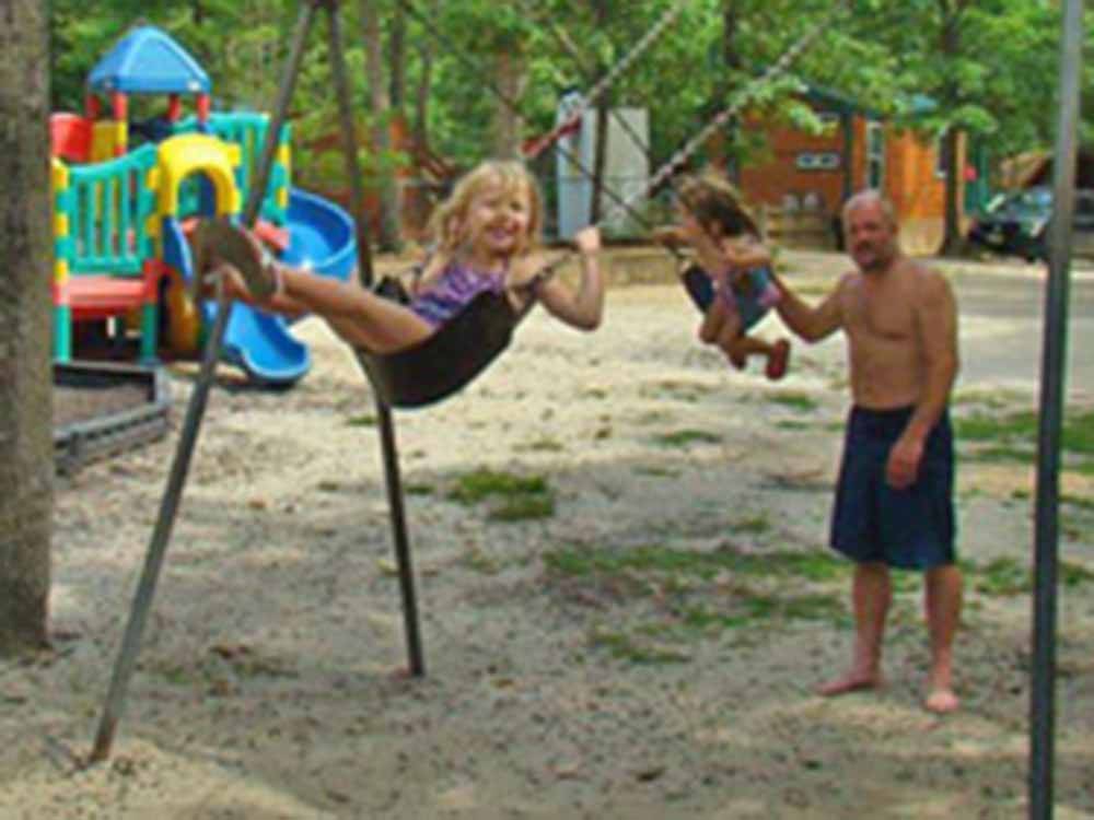 Kids enjoying the swings at the playground at ATLANTIC SHORE PINES CAMPGROUND
