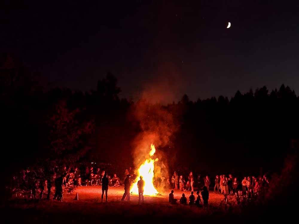 People surrounding a large bonfire at CASINI RANCH FAMILY CAMPGROUND