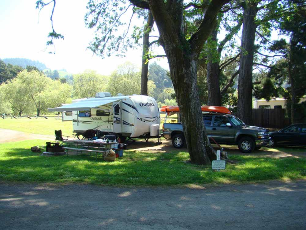A trailer and truck under a tree at CASINI RANCH FAMILY CAMPGROUND