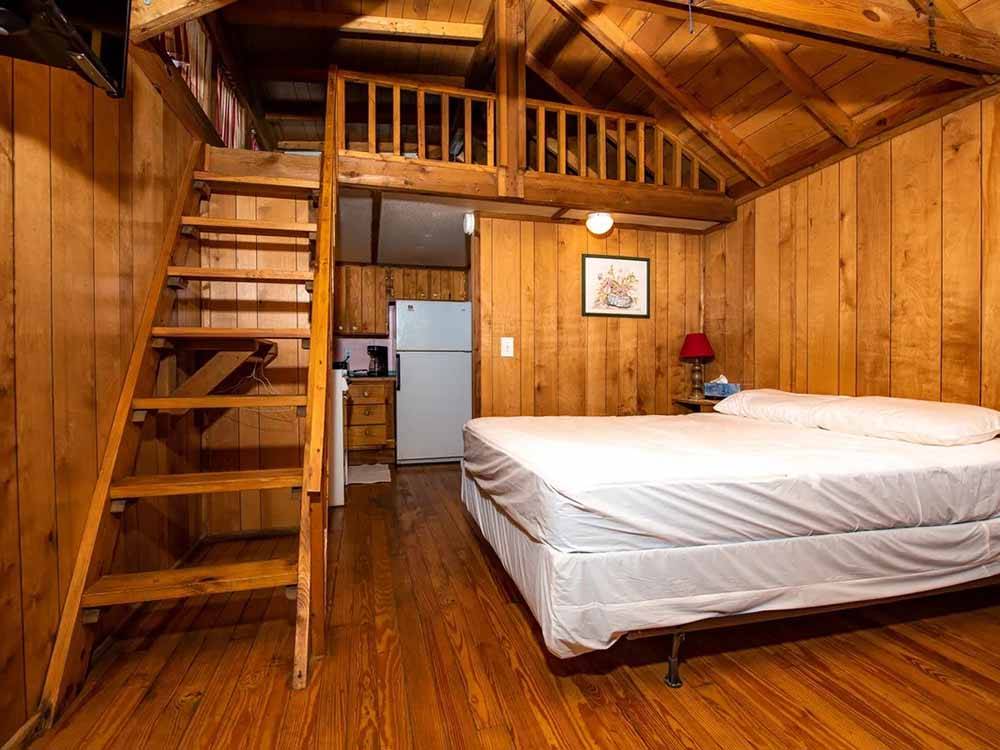Interior view of cabin with bed and loft at MOUNTAINEER CAMPGROUND