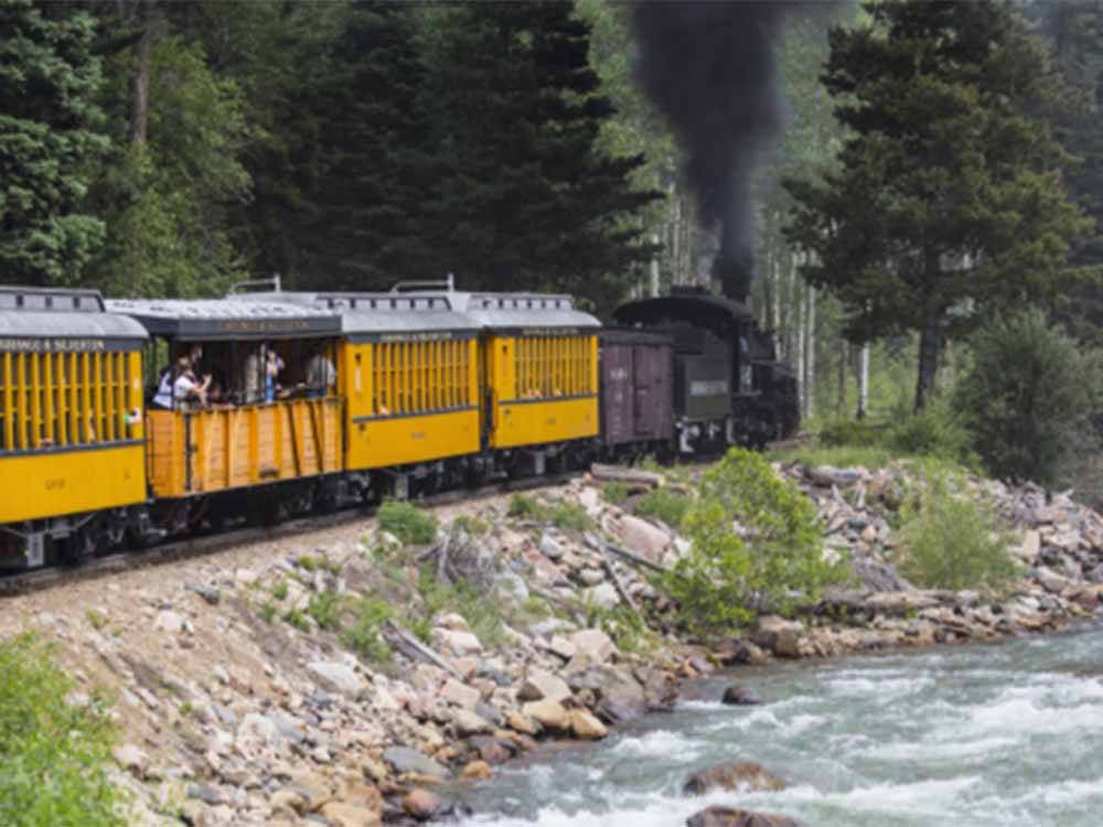 A yellow train going by the river nearby at ALPEN ROSE RV PARK