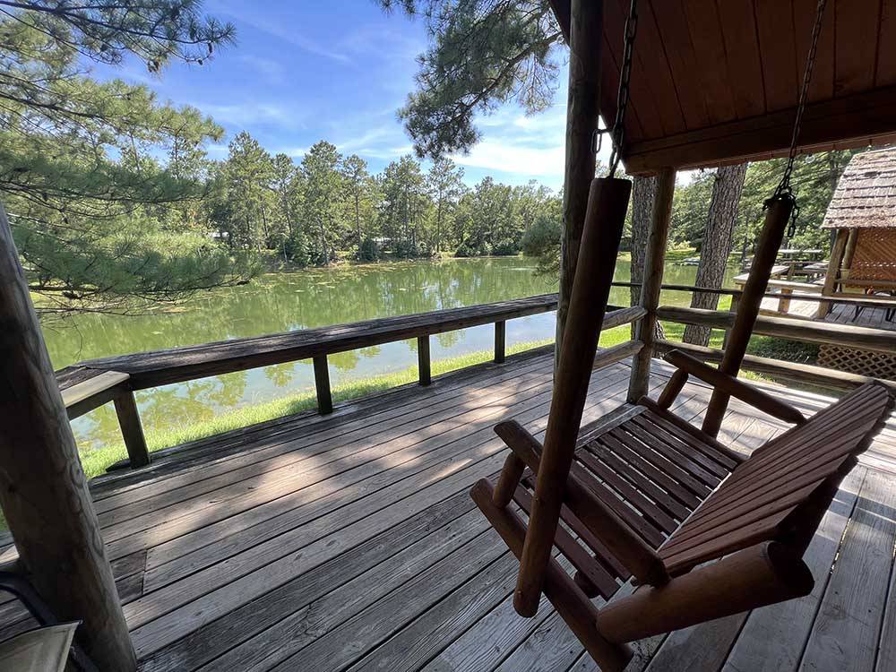 A deck with a swing overlooking the water at TALLAHASSEE EAST CAMPGROUND