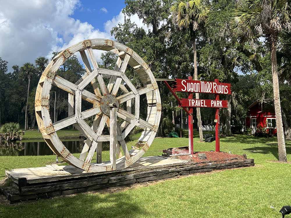 A large windmill by a sign at SUGAR MILL RUINS TRAVEL PARK