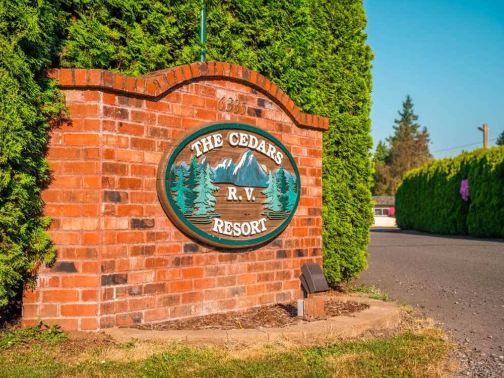 Park sign on a brick wall at THE CEDARS RV RESORT