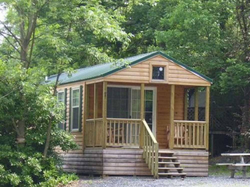 Cabin with porch surrounded by trees at ROUND TOP CAMPGROUND