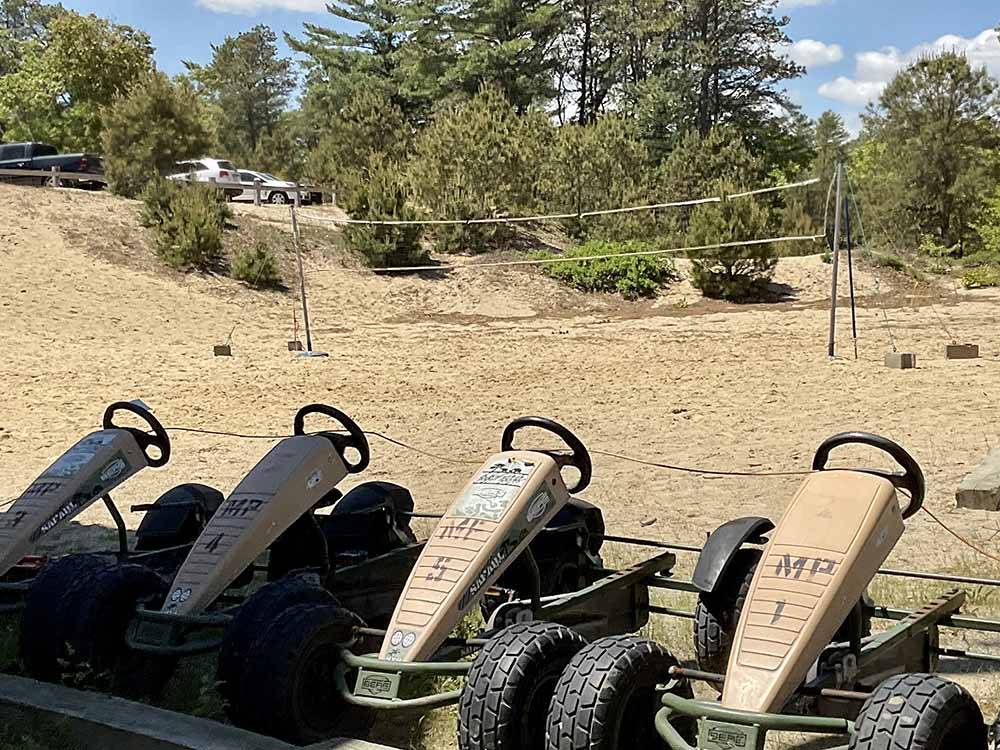 A row of pedal cars and the volleyball court at CAPE COD'S MAPLE PARK CAMPGROUND & RV PARK