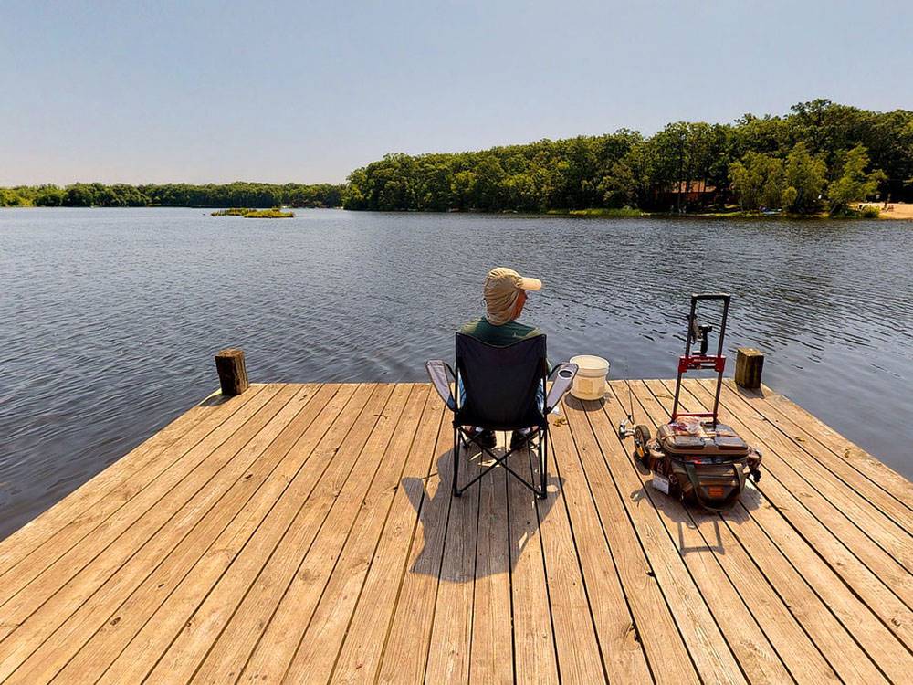 A man relaxing on a pier at OTTER LAKE CAMP RESORT