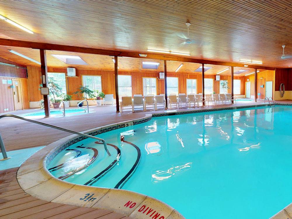 The indoor pool with chairs on the outside at OTTER LAKE CAMP RESORT