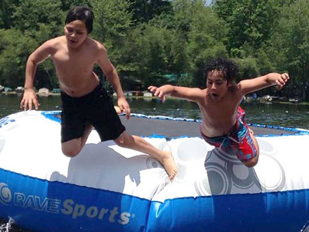 Boys jumping off a trampoline on the water at OTTER LAKE CAMP RESORT