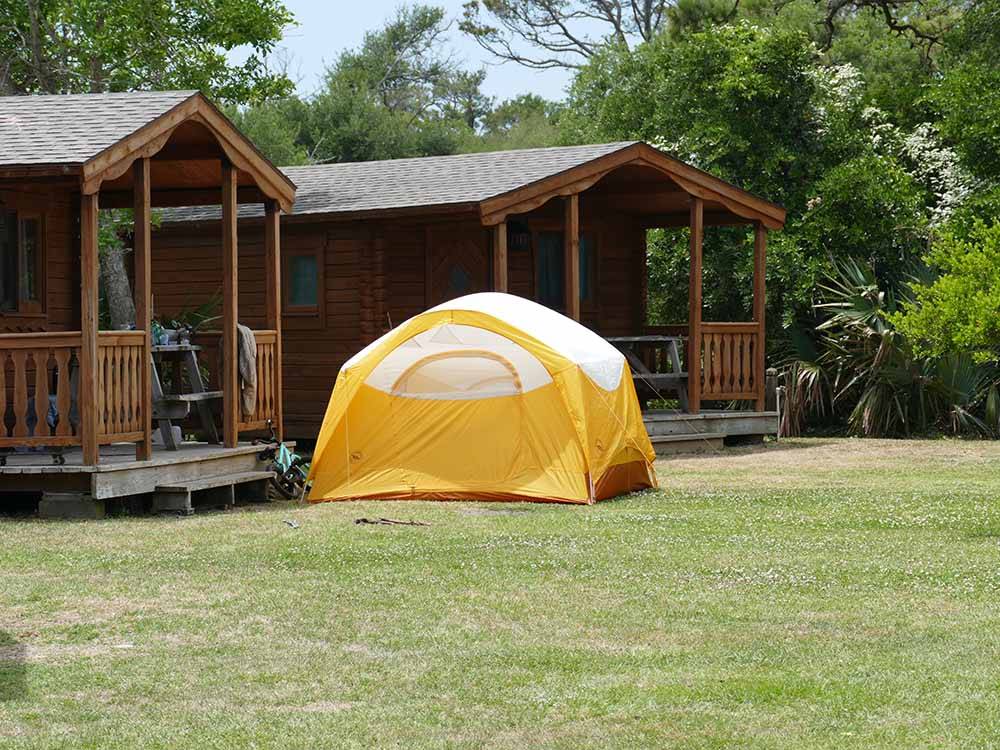 A tent in front of a row of rental cabins at FRISCO WOODS CAMPGROUND