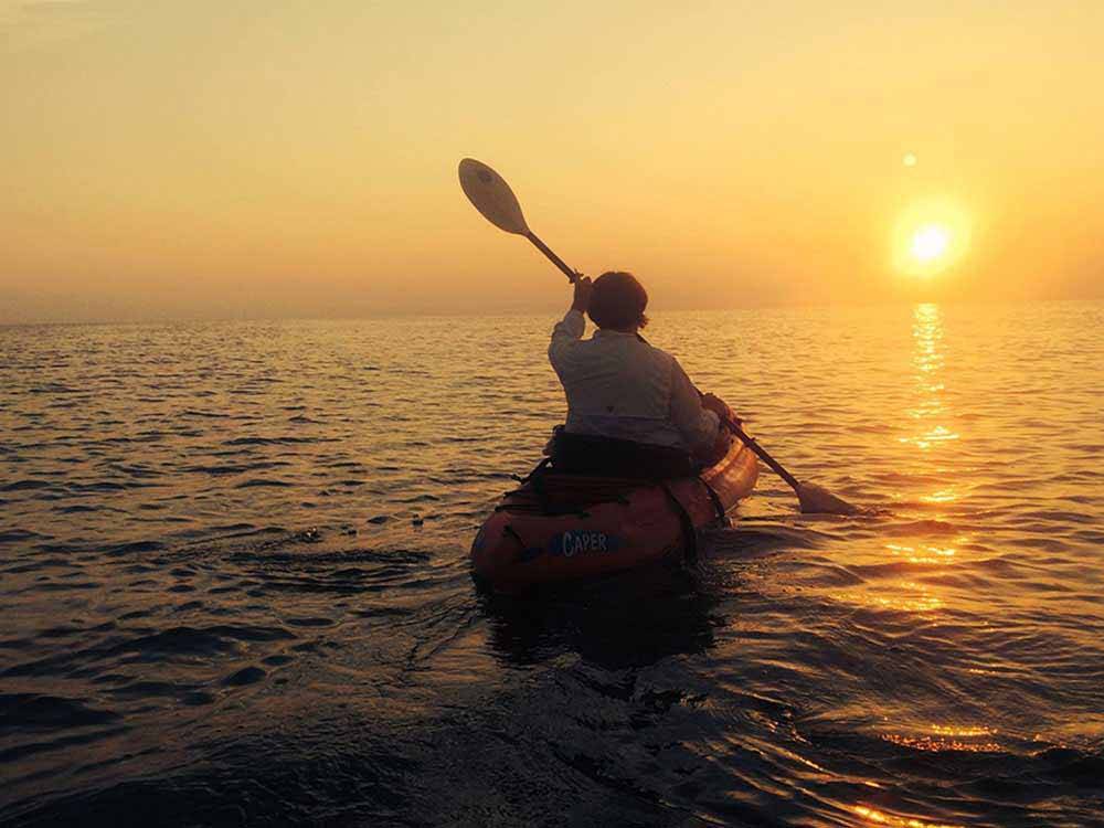 A person paddling towards the sun at FRISCO WOODS CAMPGROUND