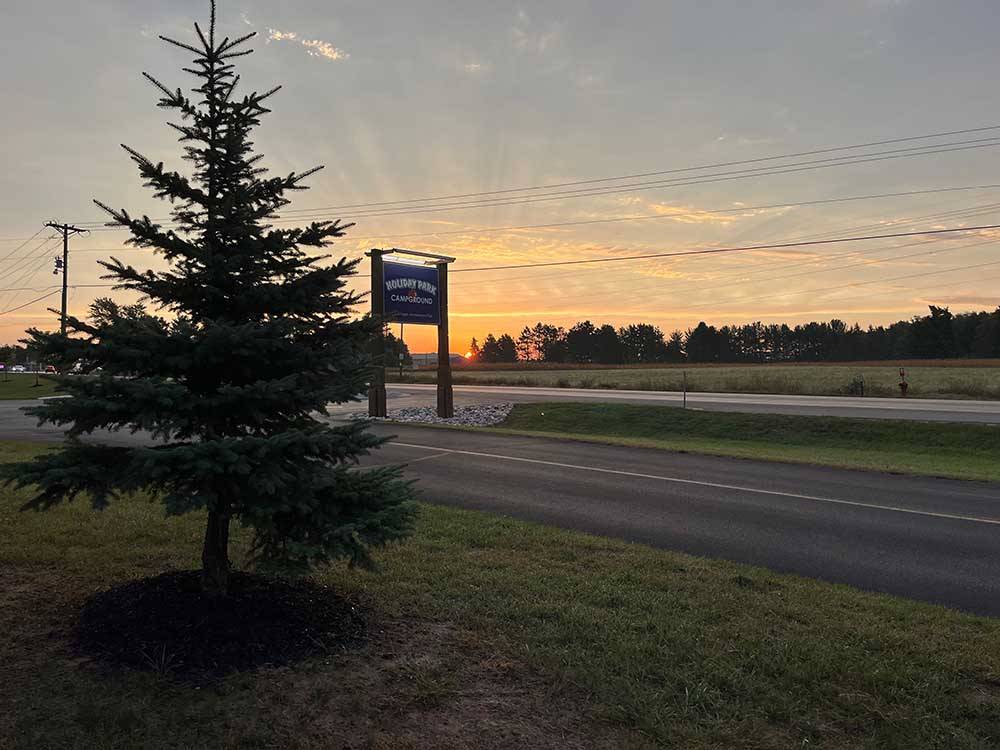 Fir tree near highway with sign of campground at HOLIDAY PARK CAMPGROUND