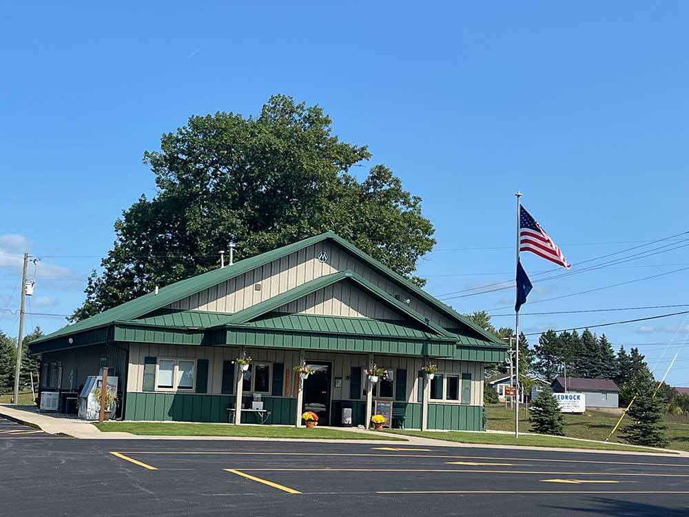 Green and tan building fronted by flags at HOLIDAY PARK CAMPGROUND