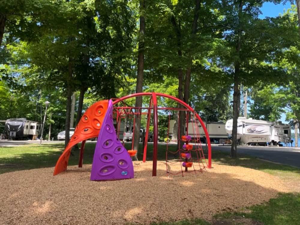 Colorful play structure with climbing and rope obstacles at HOLIDAY PARK CAMPGROUND