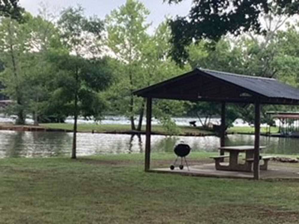 A barbecue pit and bench under a pavilion at TREASURE ISLE RV PARK