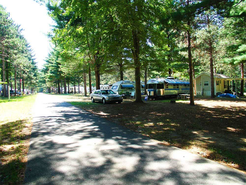 Airstream and cabin along a paved tree lined road at TWIN MILLS CAMPING RESORT