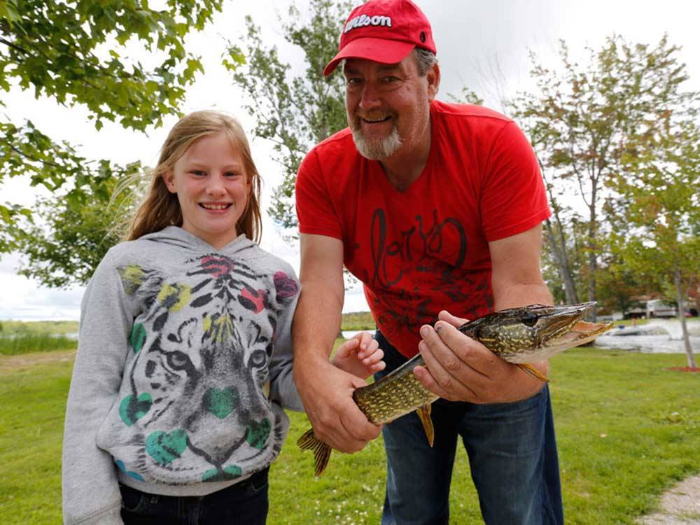 A man and girl holding a fish they caught at FISHERMAN'S COVE TENT & TRAILER PARK