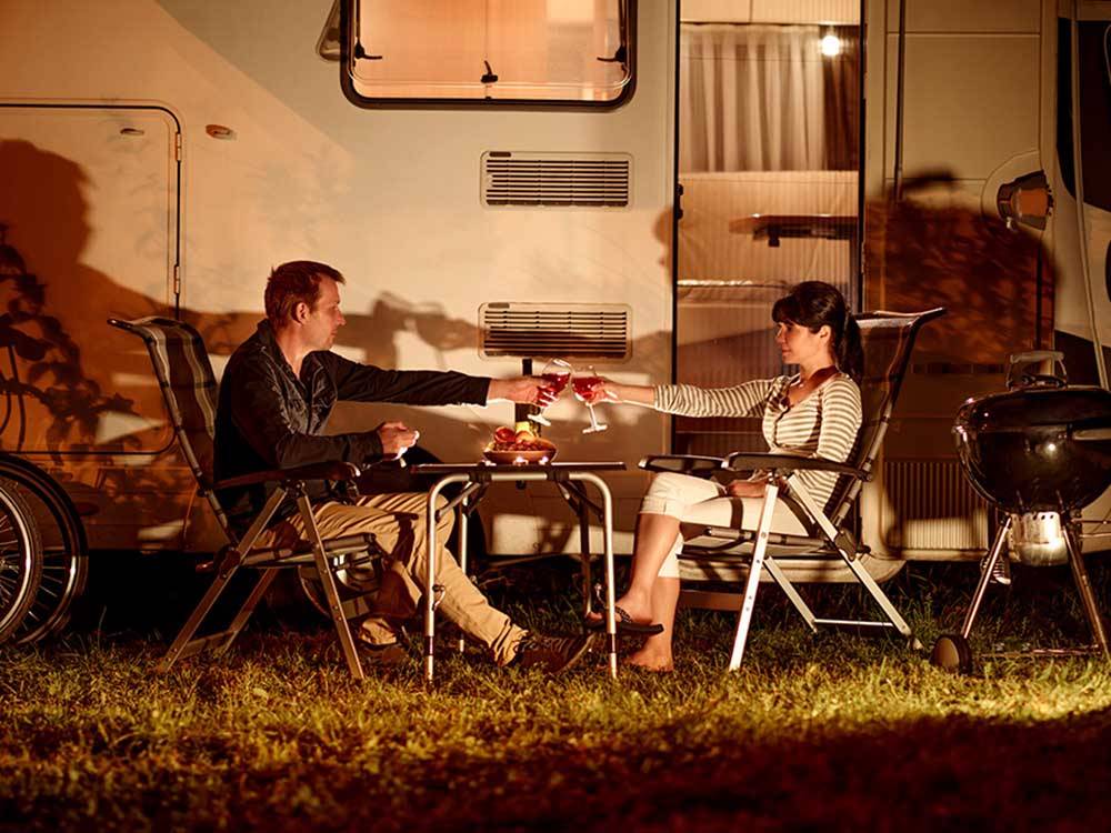 Couple enjoying the evening outside their RV at LAKE PARK CAMPGROUND & COTTAGES