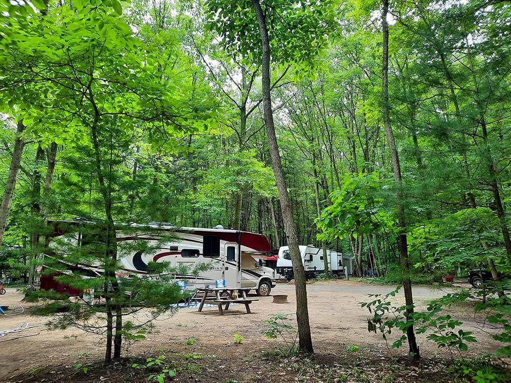 A motorhome in a dirt site surrounded by trees at The playground equipment at HUNGRY HORSE FAMILY CAMPGROUND