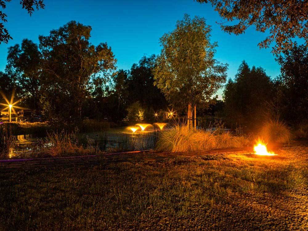 Night view of fountain on the water and blazing fire pit at VINEYARD RV PARK