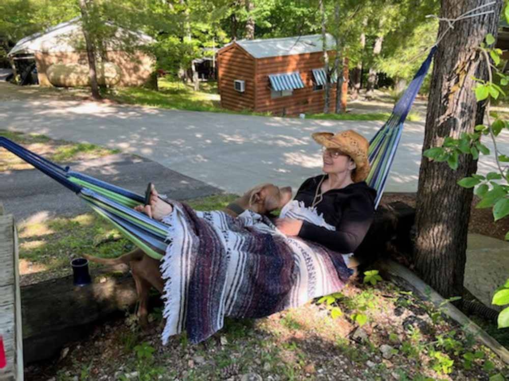 A woman and a dog in a hammock  at BLUE MOUNTAIN CAMPGROUND