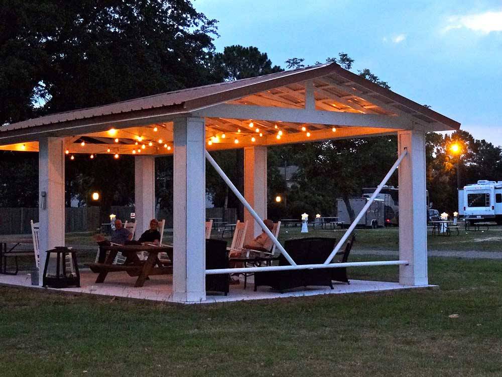 Inviting patio area with lounge chairs and decorative lighting overhead at CAJUN RV PARK