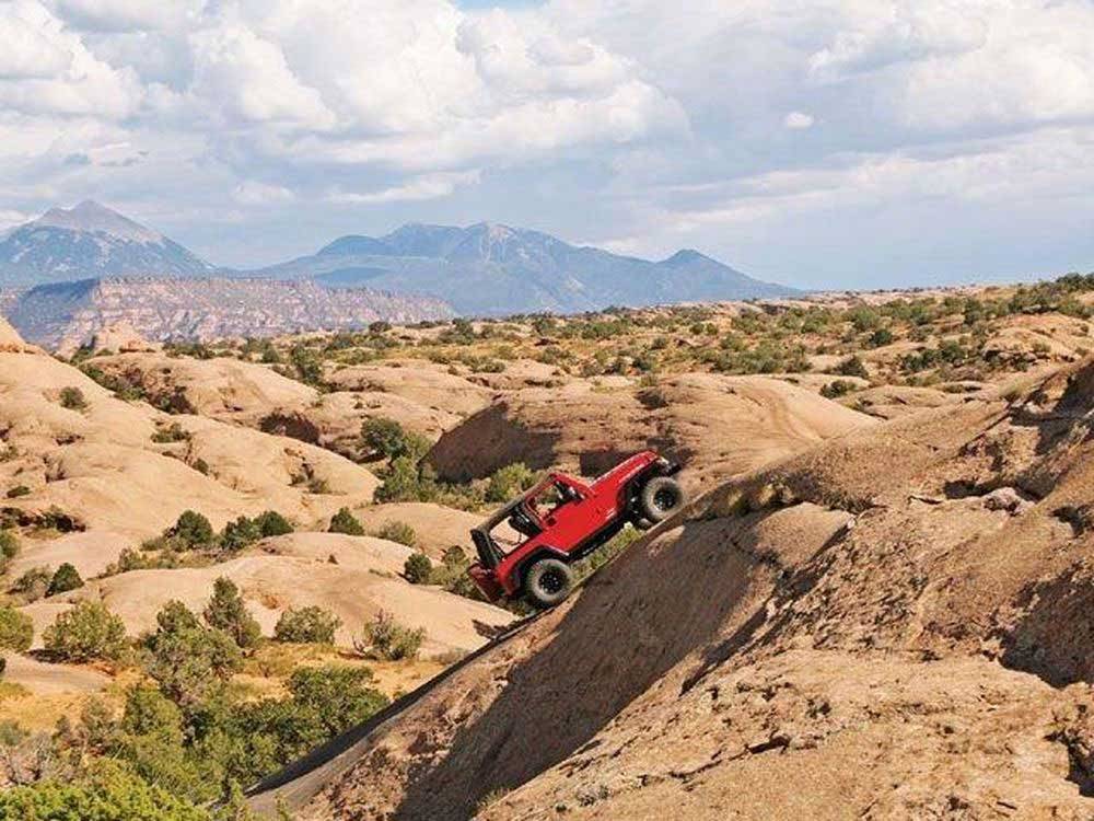 Red 4x4 jeep climbing up steep incline in the desert at SHADY ACRES RV PARK
