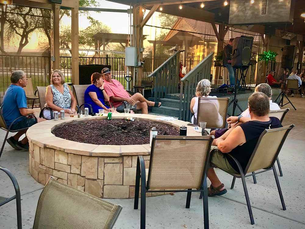 People sitting around a fire pit watching live music at RIO BEND RV & GOLF RESORT