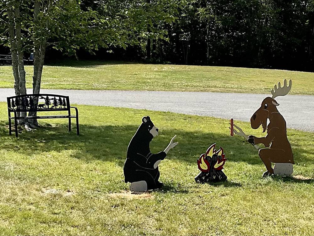 Wood sculptures of a bear, moose and fire pit at TIMBERLAND ACRES RV PARK
