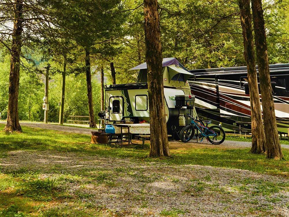 Trailer, motorhome and bikes in woodsy campsite at VOLUNTEER PARK FAMILY CAMPGROUND