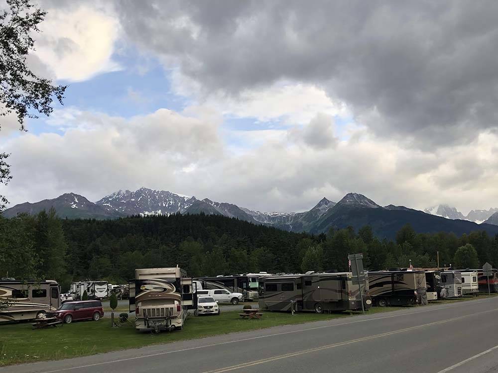 RVs parked near road as mountains loom on horizon at HAINES HITCH-UP RV PARK