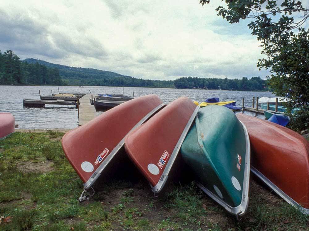 A stack of canoes by the water at TWIN TAMARACK FAMILY CAMPING & RV RESORT