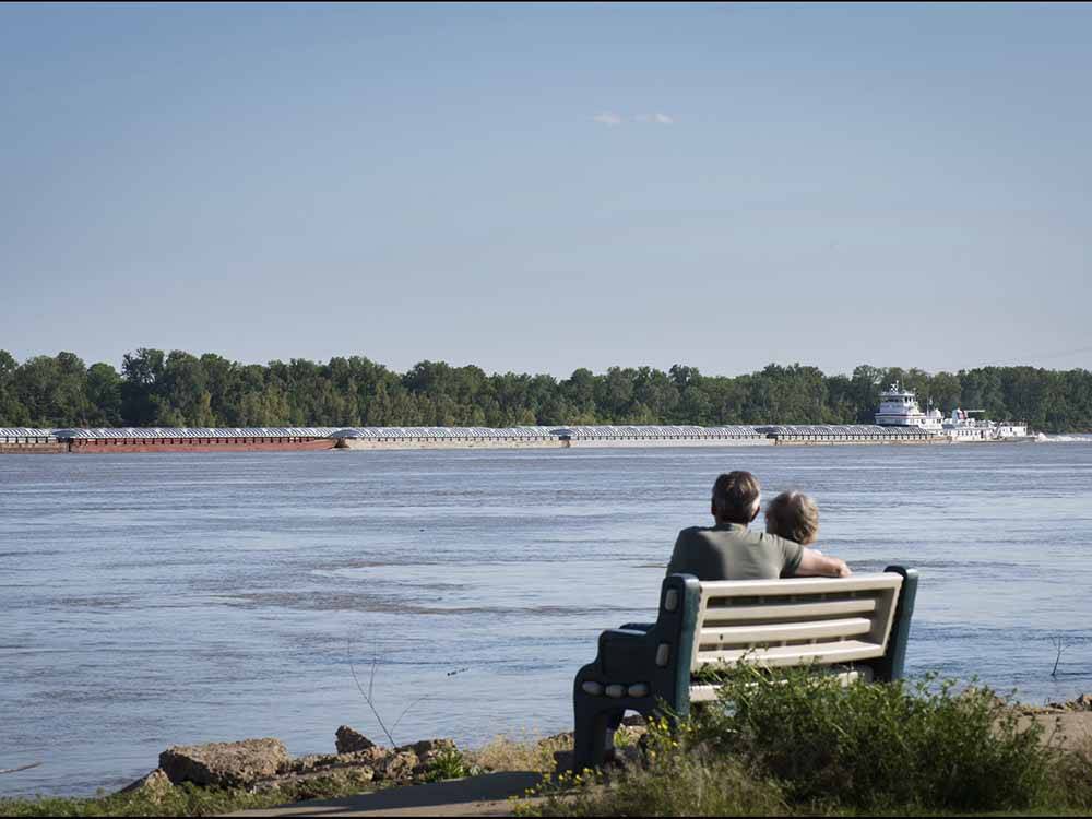 A couple sitting on a bench looking at water at TOM SAWYER'S RV PARK