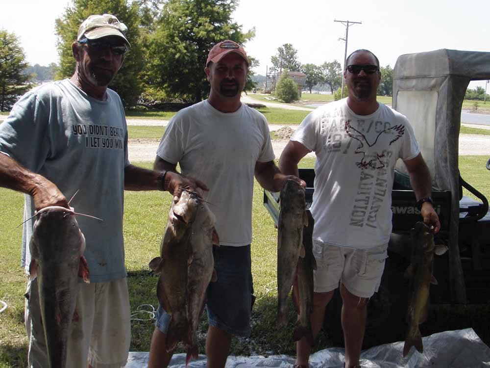 Three men holding fish at TOM SAWYER'S RV PARK