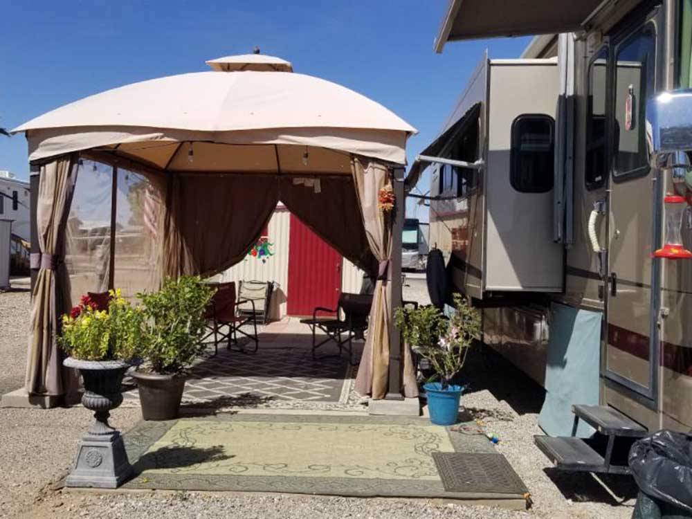 A tent with chairs next to a RV at MISSION VIEW RV RESORT