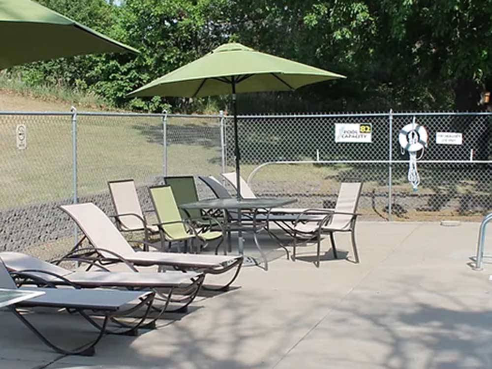 Chaise lounges and tables poolside at ST CLOUD CAMPGROUND & RV PARK
