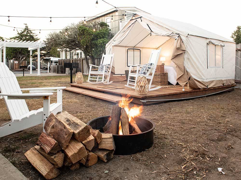 A glamping canvas cabin with a fire in front at MARINA DUNES RV RESORT