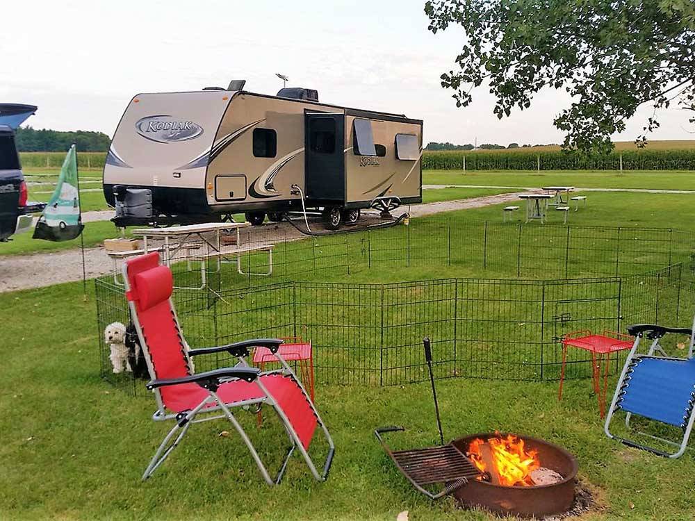 Folding chairs near fire pit with RV in background at AMANA RV PARK & EVENT CENTER