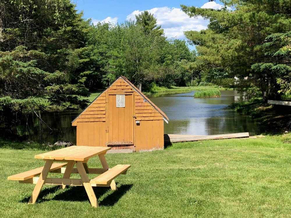 A picnic table and small shed near water at PAUL BUNYAN CAMPGROUND