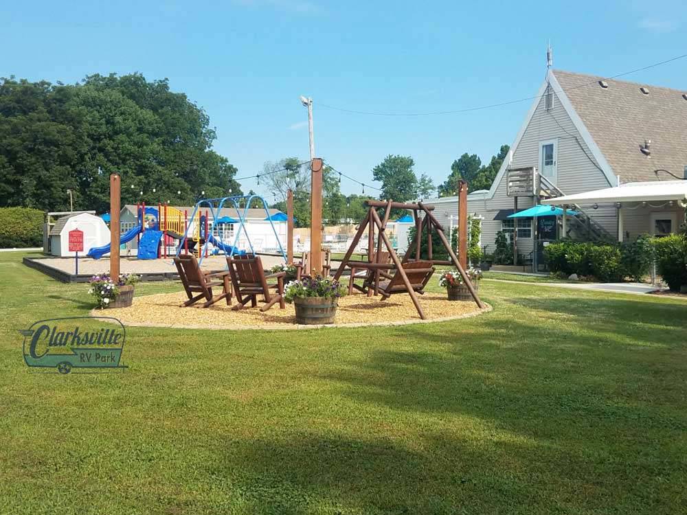 The playground set next to wooden chairs and swing at CLARKSVILLE RV RESORT BY RJOURNEY