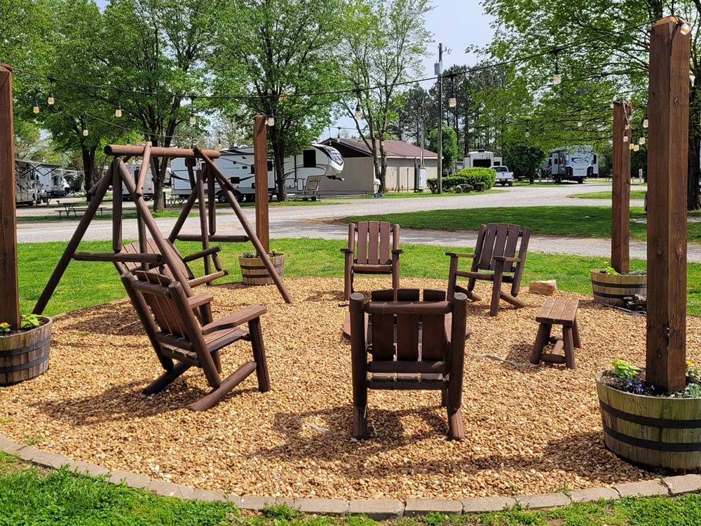 Wooden chairs and swing with a fire pit at CLARKSVILLE RV RESORT BY RJOURNEY