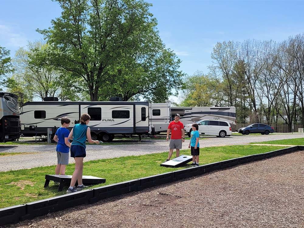 A dad and his kids playing cornhole at CLARKSVILLE RV RESORT BY RJOURNEY