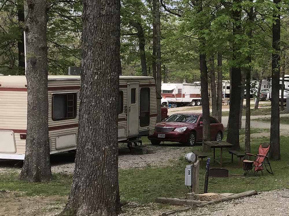 A gravel RV site under trees at RUSTIC TRAILS RV PARK