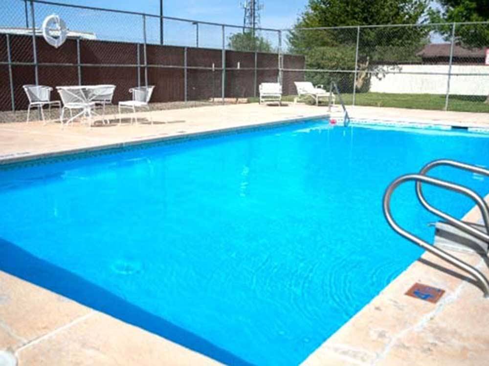 Rectangular pool with white table and chairs nearby at TOWN & COUNTRY RV PARK