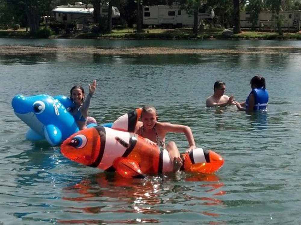 Kids playing on inflatable fish in the lake at LEHMAN'S LAKESIDE RV RESORT