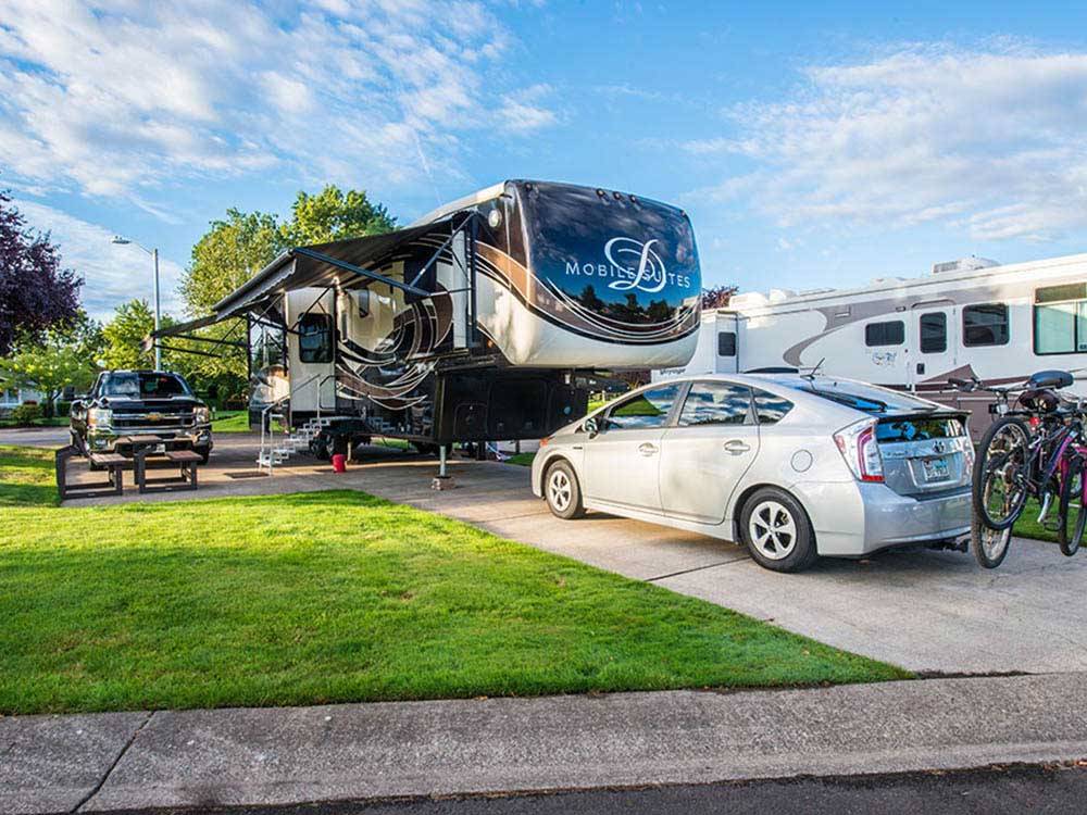 Chevy Silverado and Toyota Prius parked along large RV at OLDE STONE RV RESORT