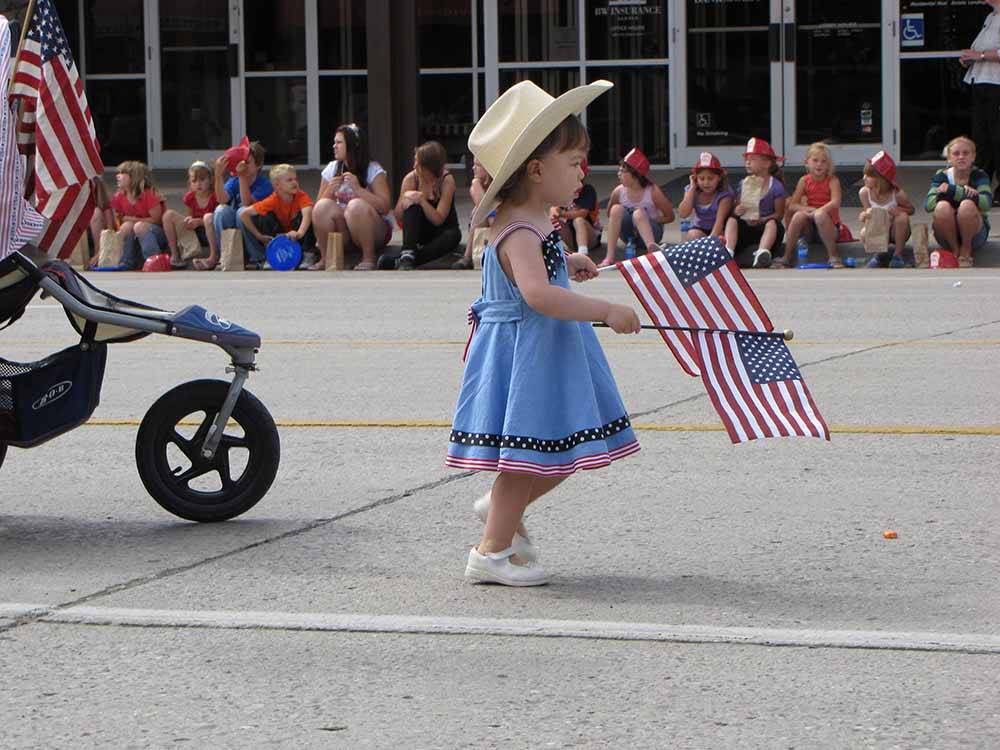 A little girl holding American flags in a parade at CODY YELLOWSTONE