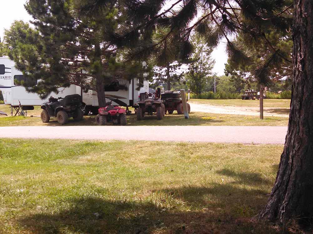 A group of ATVs under a tree at SHERWOOD FOREST CAMPGROUND