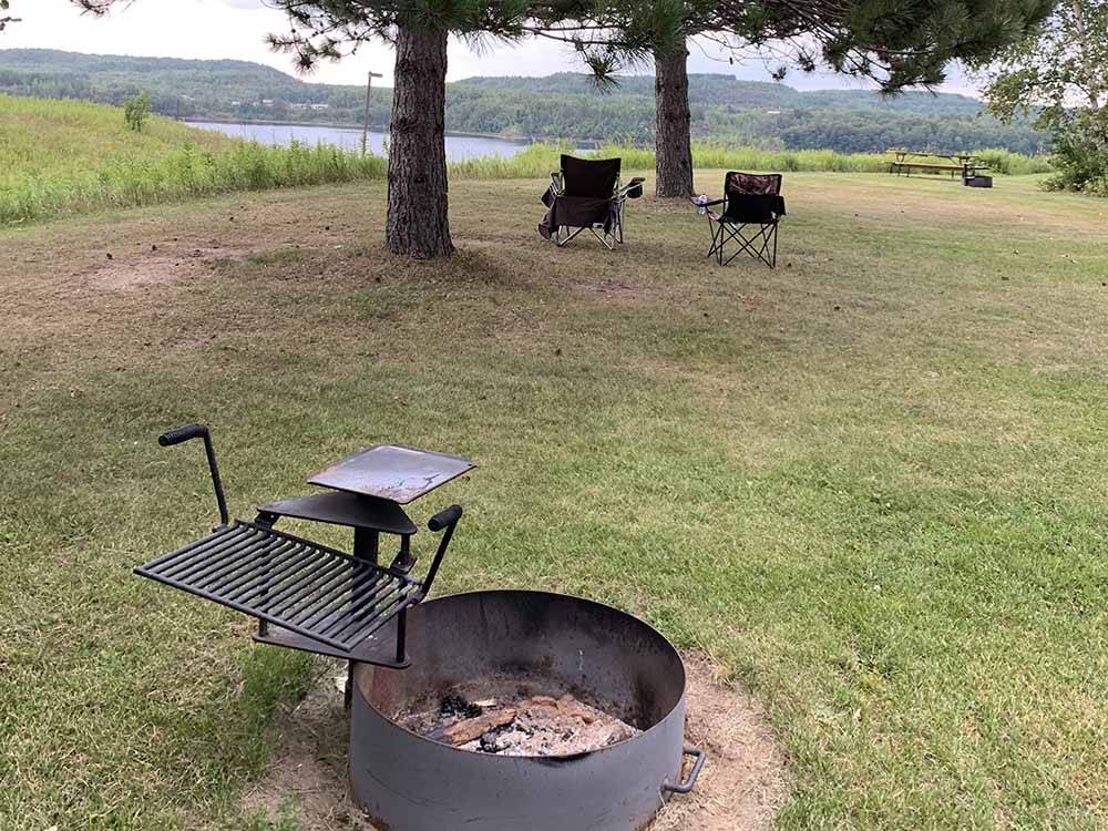 A fire pit and chairs overlooking the water at SHERWOOD FOREST CAMPGROUND